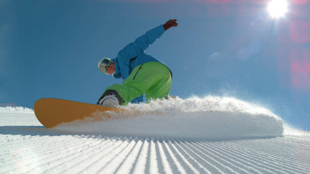 istock CLOSE UP: Cheerful snowboarder carving and spraying snow into camera 1186506382