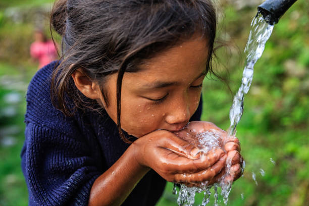 Nepali girl drinking water, village near Annapurna Range Nepali girl drinking fresh water, village in Annapurna Conservation Area. annapurna circuit photos stock pictures, royalty-free photos & images