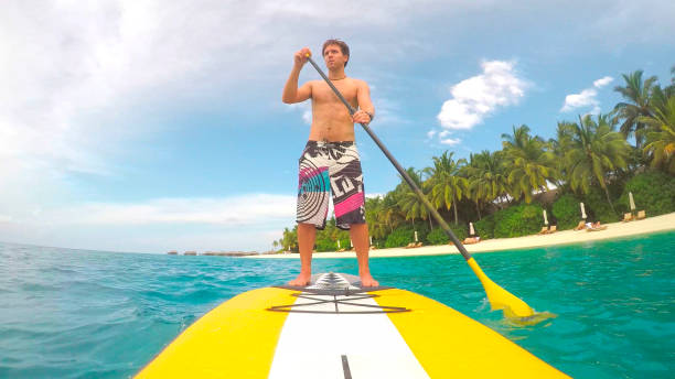 istock Young man stand up paddling in exotic Maldives 1186508436