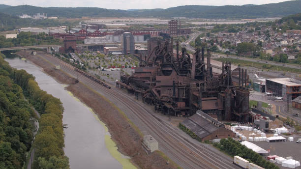 istock AERIAL: Old working ironworks built near big river in small industrial town 1186508636