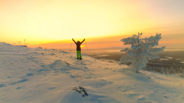 antenna donna attiva con le ciasli che spazza le ciasli sul pendio innevato e alza le braccia in cima - sunrise mountain winter arctic foto e immagini stock
