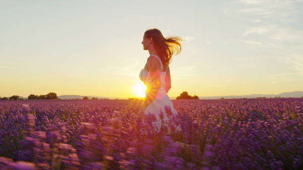 istock Young woman running through lavender field at sunset 1186512654