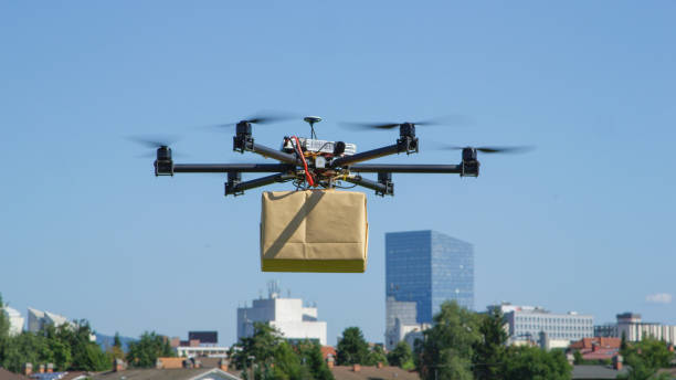 primo passo: consegna di droni uav che consegnano un grande pacchetto post marrone nella città urbana - city of post foto e immagini stock