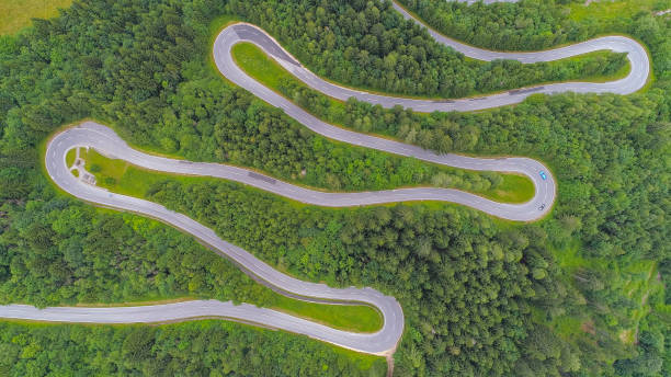 aerial:シャープなヘアピンターンで風光明媚な山の高速道路に沿って運転車 - distorted ストックフォトと画像