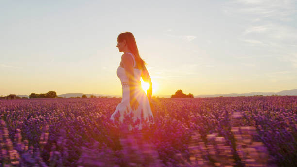 istock Young woman running through lavender field at sunset 1186512688