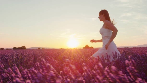 istock Young woman running through lavender field at sunset 1186512711