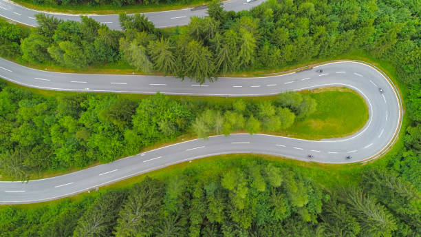 istock AERIAL TOP DOWN: Motorcycles speeding through sharp turns on scenic winding road 1186512733