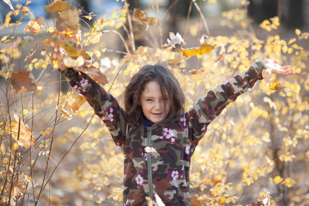 istock Little girl throws leaves in the fall 1186512740