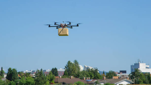 istock CLOSE UP: UAV drone logistics delivering big brown post package into urban city 1186513354