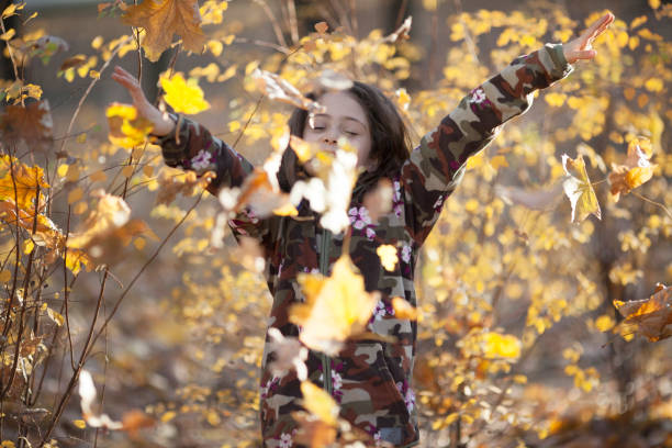 istock Little girl throws leaves in the fall 1186513438