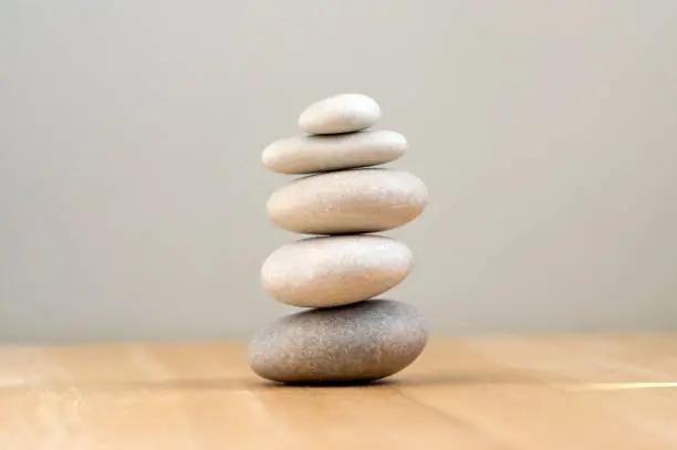 Photo of Harmony and balance, cairns, simple poise pebbles on wooden light white gray background, simplicity rock zen sculpture