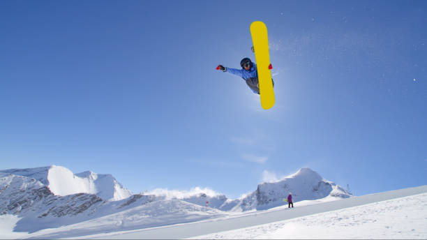 istock Young pro snowboarder jumping in half pipe in sunny snow park 1186514356