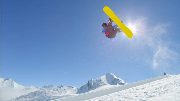 istock Young pro snowboarder jumping over the sun in half pipe snow park 1186514517