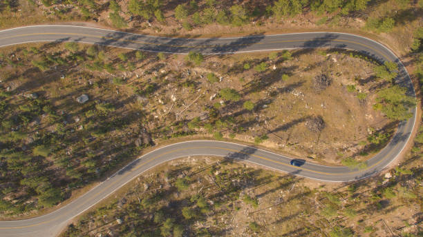 istock AERIAL: Two vehicles driving on winding switchback road in sunny mountain forest 1186514531