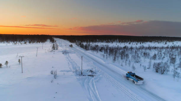 aerial: schneepflug fahrt und pflügen durch schneebedeckte autobahn inmitten von wald - agricultural equipment flash stock-fotos und bilder