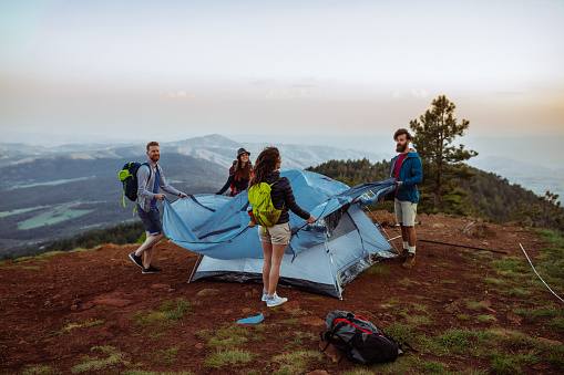 Shot of four friends setting up their tent in the mountains