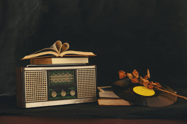 Heart-shaped books placed on retro radio receivers with dried flowers and old CD. stock photo