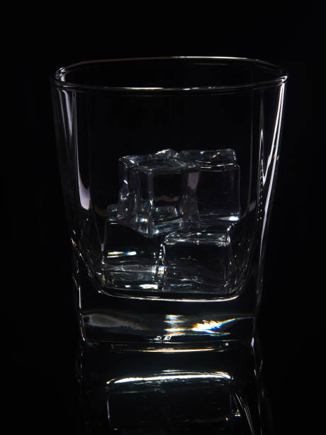 istock Glass of whiskey with ice on a black background with reflection 1186519076
