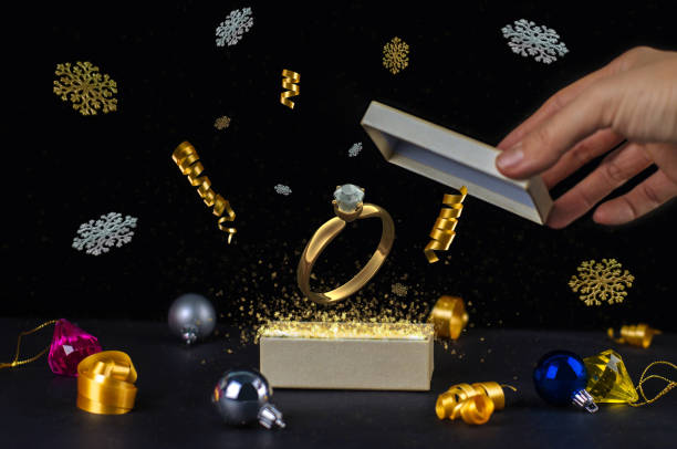 Open Magic Christmas Gift Box with presents, decoration, golden dust, particles, ribbon and gold diamond ring. New Year gifts stock photo