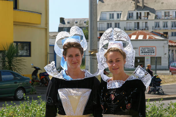 Two young ladies in traditional Breton costume with lace headgear. Morbihan, Brittany - September 2014. Two young ladies dressed in traditional Breton clothing including intricate headdress. headdress stock pictures, royalty-free photos & images