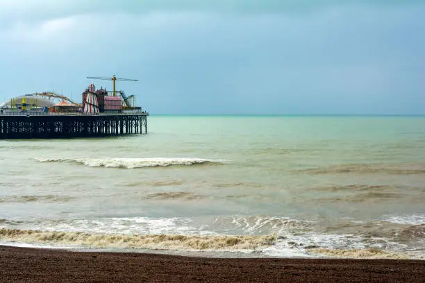 Photo of The shingle beach at Brighton, East Sussex, UK in autumn and the Brighton Palace Pier on a cloudy day