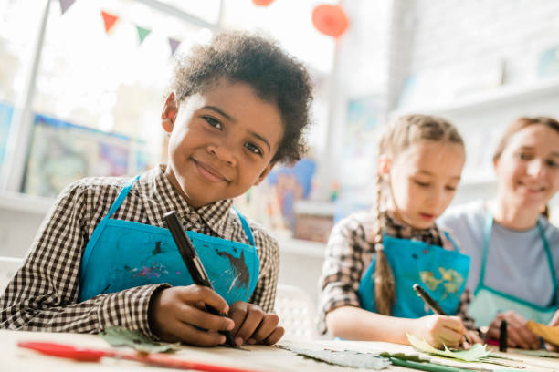 istock Happy schoolboy with highlighter looking at you while sitting by desk at lesson 1186533668