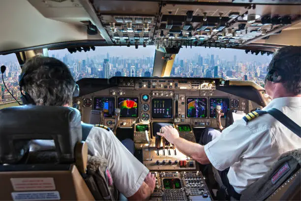 The cockpit of a modern passenger aircraft in flight. A view from the cockpit to the skyscrapers of the business center of a huge city.