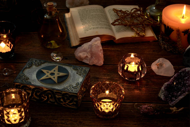 istock Esoteric or mystical still life with a box and a few burning candles, a pentagram next to an open book. Pendulum and precious stones on old wooden table top. 1186538232