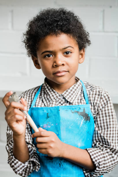 istock Creative and adorable schoolboy with paintbrush while standing in isolation 1186538570