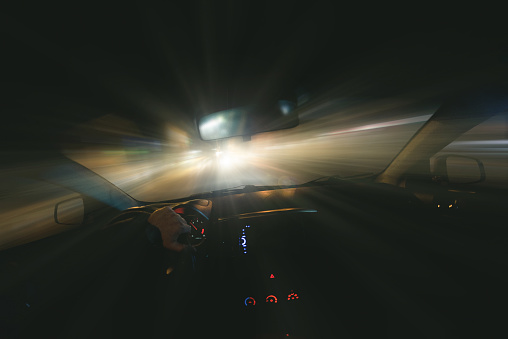 Driver is driving a car on night road on high velocity speed concept. First person view.
