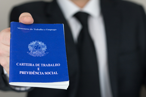 Sao Paulo, Brazil - November 2019: Business man wearing suit and tie holding a portfolio work permit. (Translation: Ministry of Labor and Social Security of Brazil).