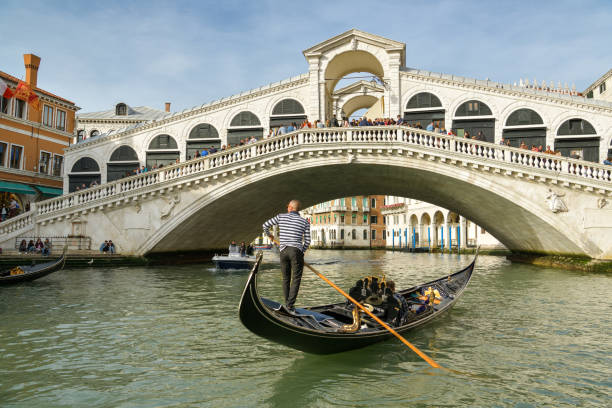 góndola acercándose al superpoblado puente ponte rialto en canal grande en venecia, italia - venice italy rialto bridge italy gondola fotografías e imágenes de stock
