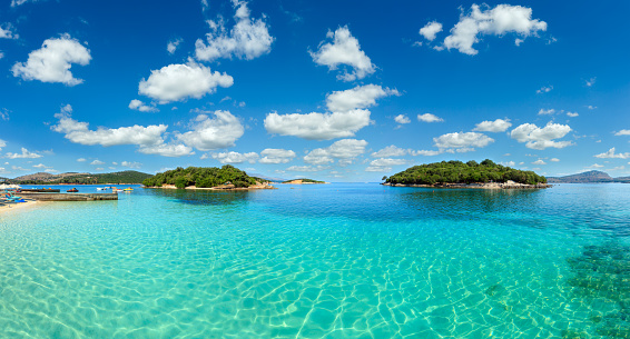 Beautiful Ionian Sea with clear turquoise water and morning summer coast view from beach (Ksamil, Albania). Multi shots stitch panorama.