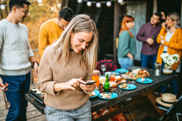 istock Young woman text messaging at garden party 1186553222