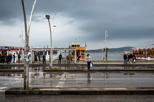 A woman crosses the street on a rainy afternoon in the port of Ayvalik, Turkey