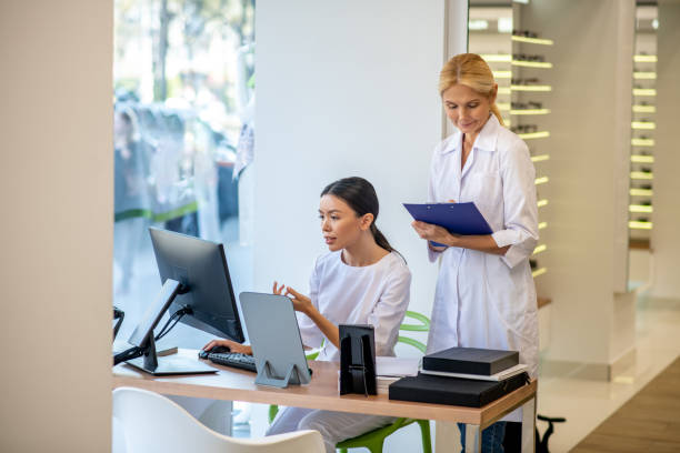 istock Blonde-haired ophthalmologist helping her assistant perform working tasks 1186562561