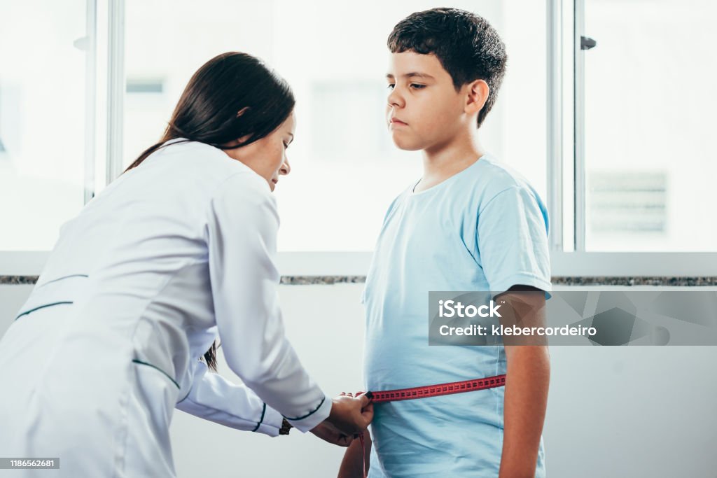 Female doctor measuring overweight boy in clinic Overweight Stock Photo