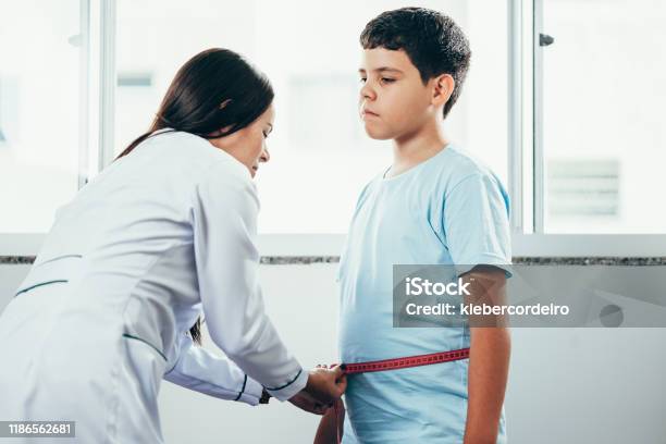 Female Doctor Measuring Overweight Boy In Clinic Stock Photo - Download Image Now - Overweight, Child, Teenager
