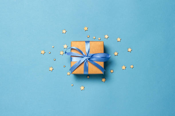 istock Gift box with blue ribbon on a blue background with decorative stars. Gift concept for a loved one, holiday .Flat lay, top view 1186564451