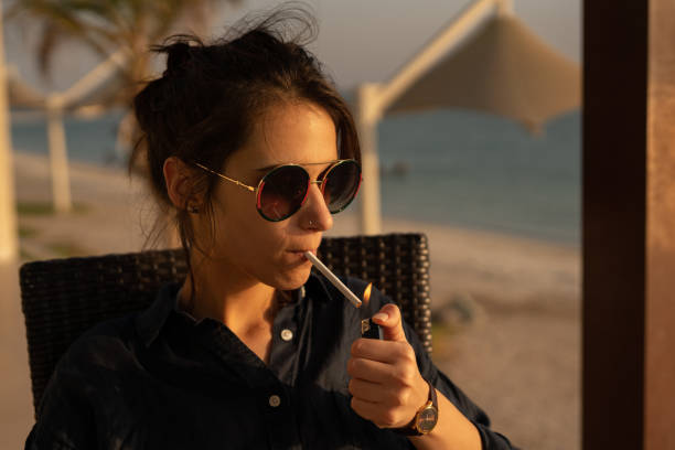 bella signora fuma sulla spiaggia durante il tramonto ad abu dhabi - umbrella beach sex symbol white foto e immagini stock