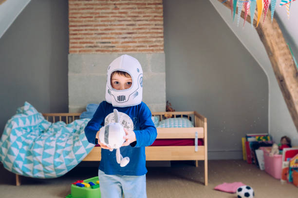 retrato de un niño con un disfraz de astronauta y jugando con una nave espacial. - super moon fotografías e imágenes de stock