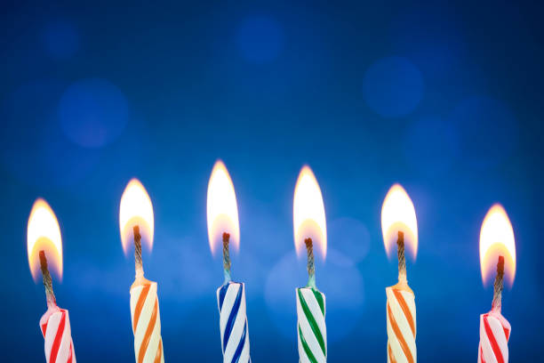 kolorowe i śmieszne świece urodzinowe są zapalone na niebieskim tle. przyjęcie urodzinowe, rocznica lub niektóre uroczystości, gdzie świece są gotowe dla kogoś, aby je wysadzić. tło z pięknym bokeh - bright brightly lit vibrant color burning zdjęcia i obrazy z banku zdjęć