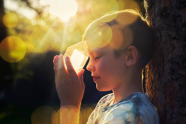Healing with crystal on the sunny day, boy holding crystal in light