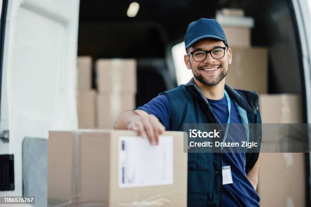 Young Happy Delivery Man With Cardboard Boxes Looking At Camera Stock Photo - Download Image Now