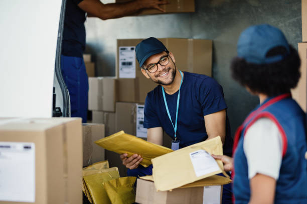 istock Happy courier communicating with female coworker while preparing packages for delivery in a van. 1186578221