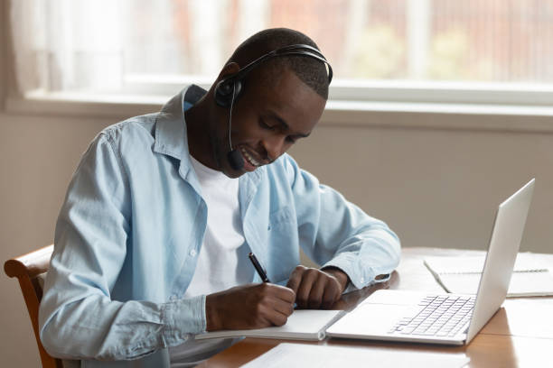 istock Focused biracial man in headset writing studying at laptop 1186579703