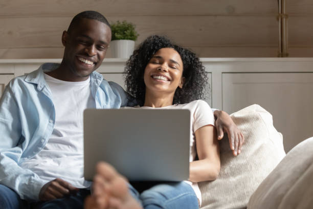 istock Happy biracial couple relax laugh using laptop at home 1186579748