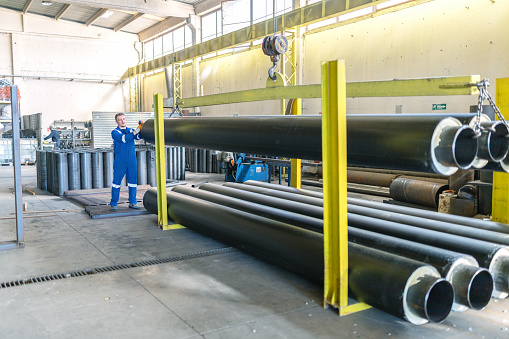 Factory worker lifting the gas pipe with crane