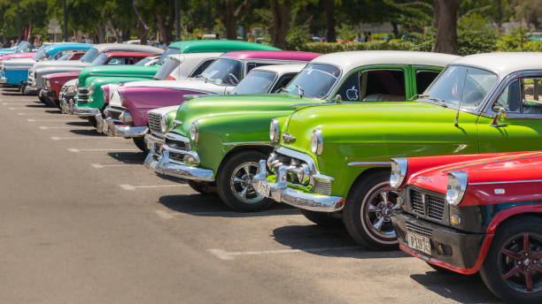 Havana classic car in colorful row Havana, Cuba - July 23, 2018; A row of typical colorful Cuban oldtimer classic cars standing in line during day time on a parking lot metallic red chrome pattern stock pictures, royalty-free photos & images