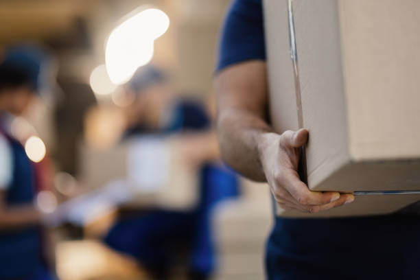 istock Close-up of a worker carrying cardboard box while making a delivery. 1186582485